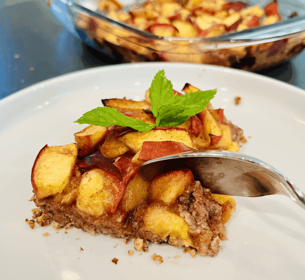 A slice of peach cobbler on a white plate