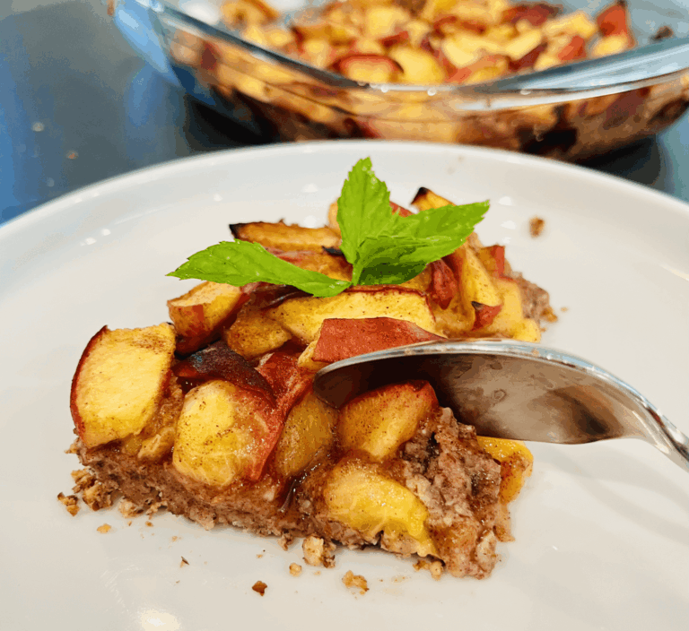 A slice of peach cobbler on a white plate